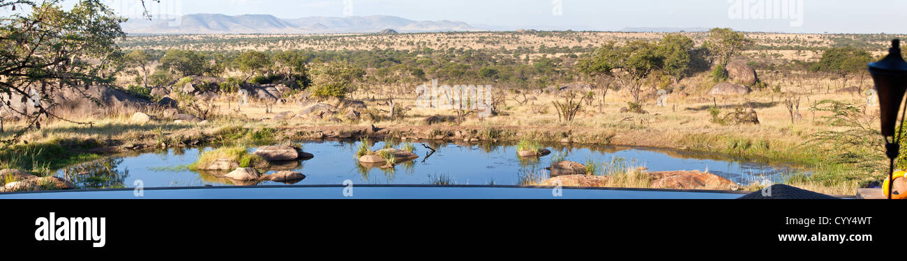 View from the back pool deck of the Bilia Lodge with infinity pool and watering hole below. Serengeti National Park, Tanzania Stock Photo