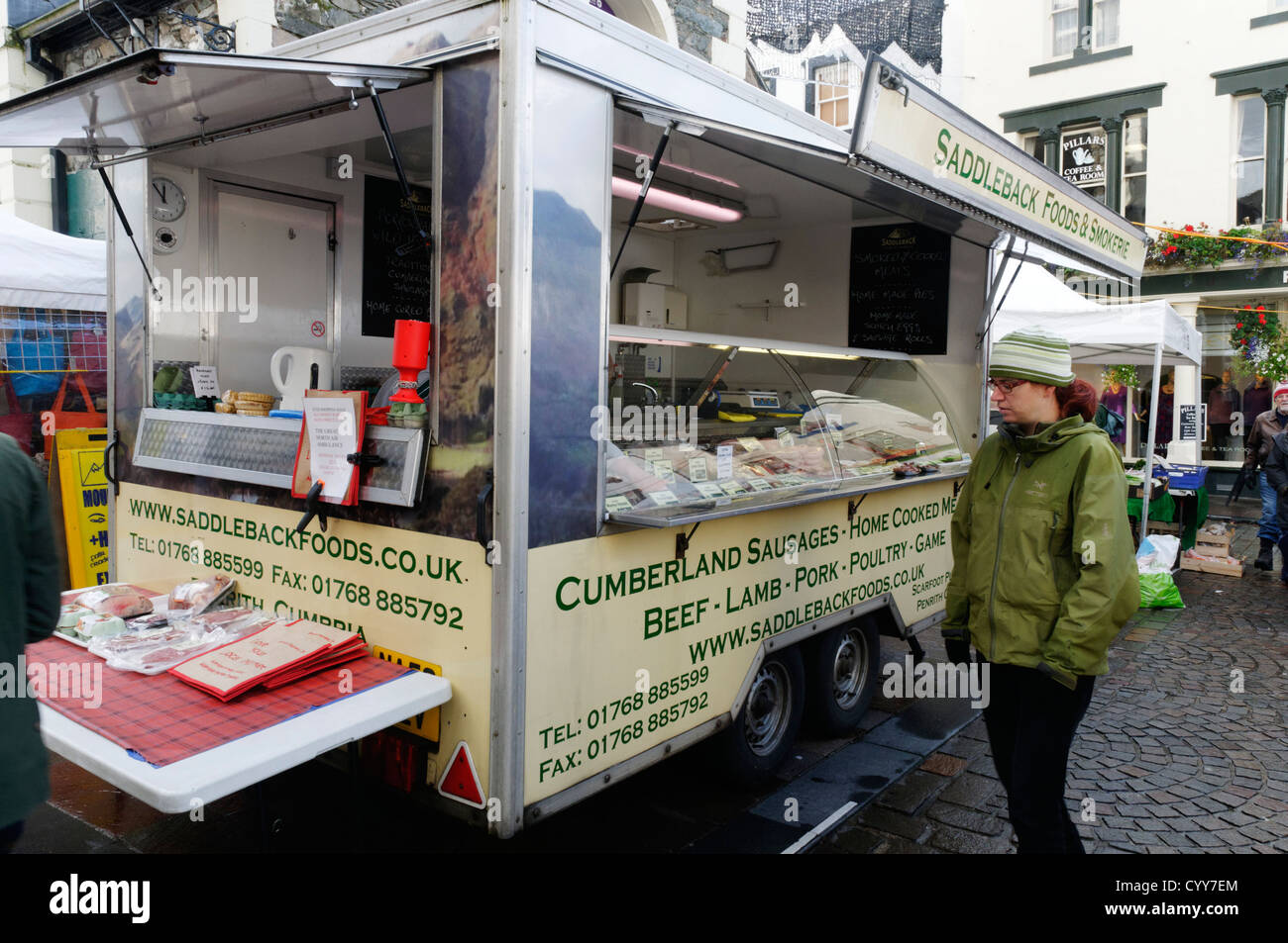A woman looking at a display of local meat products on a market in