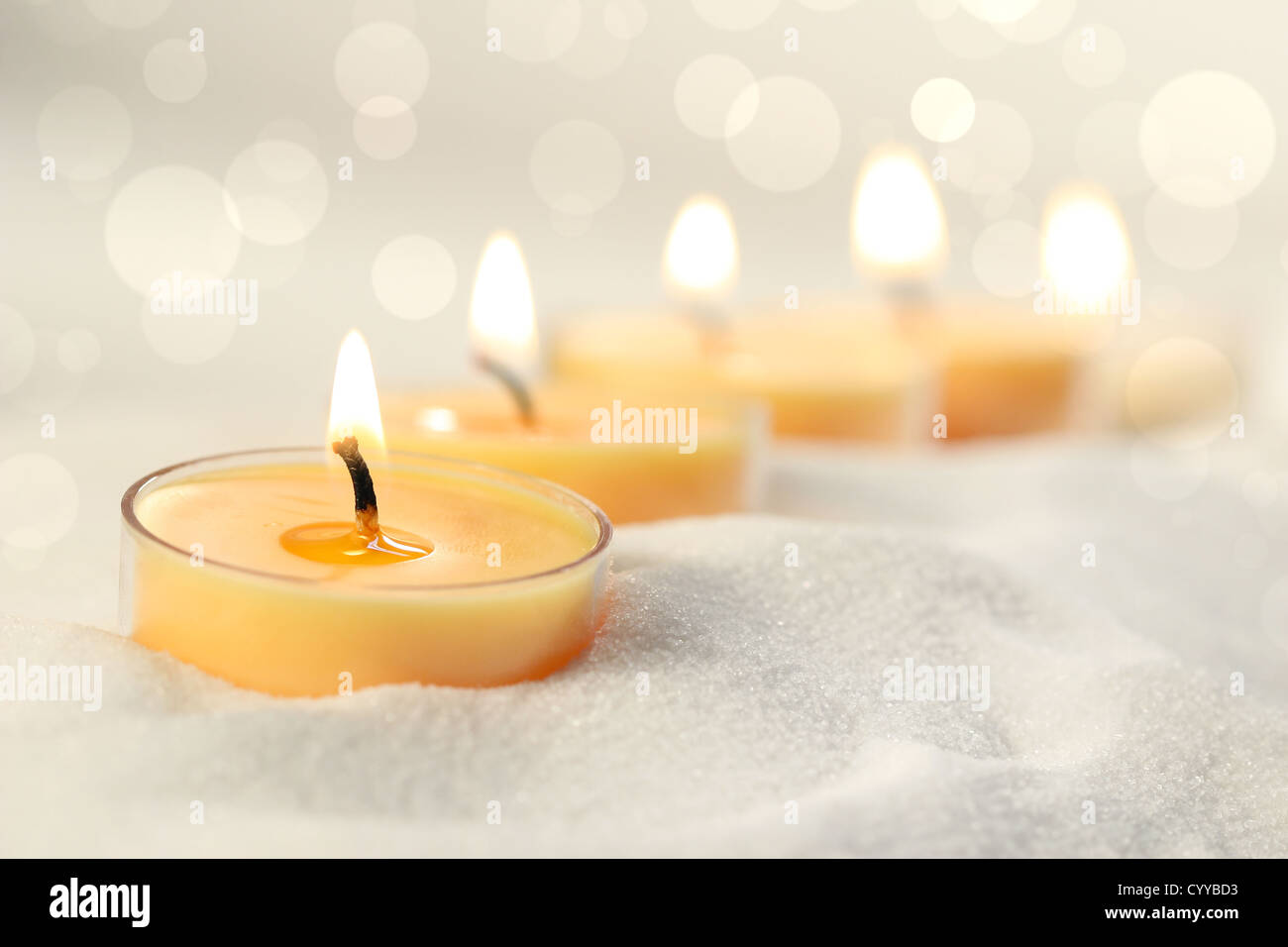 Votive candles in sand lit and arranged for ambiance Stock Photo