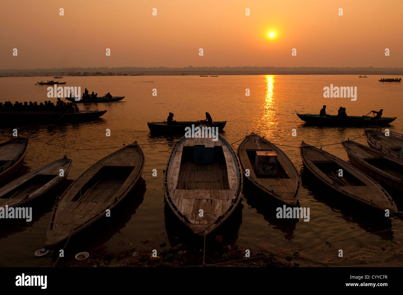 A stunning sunrise looking over the holiest of rivers in India. The Ganges. Silhouettes of boats dapple the horizon. Stock Photo