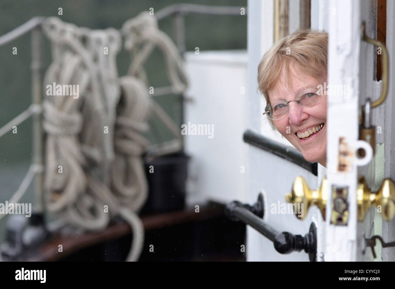 Woman peeking out door of small cruise boat in Southeast Alaska. Stock Photo