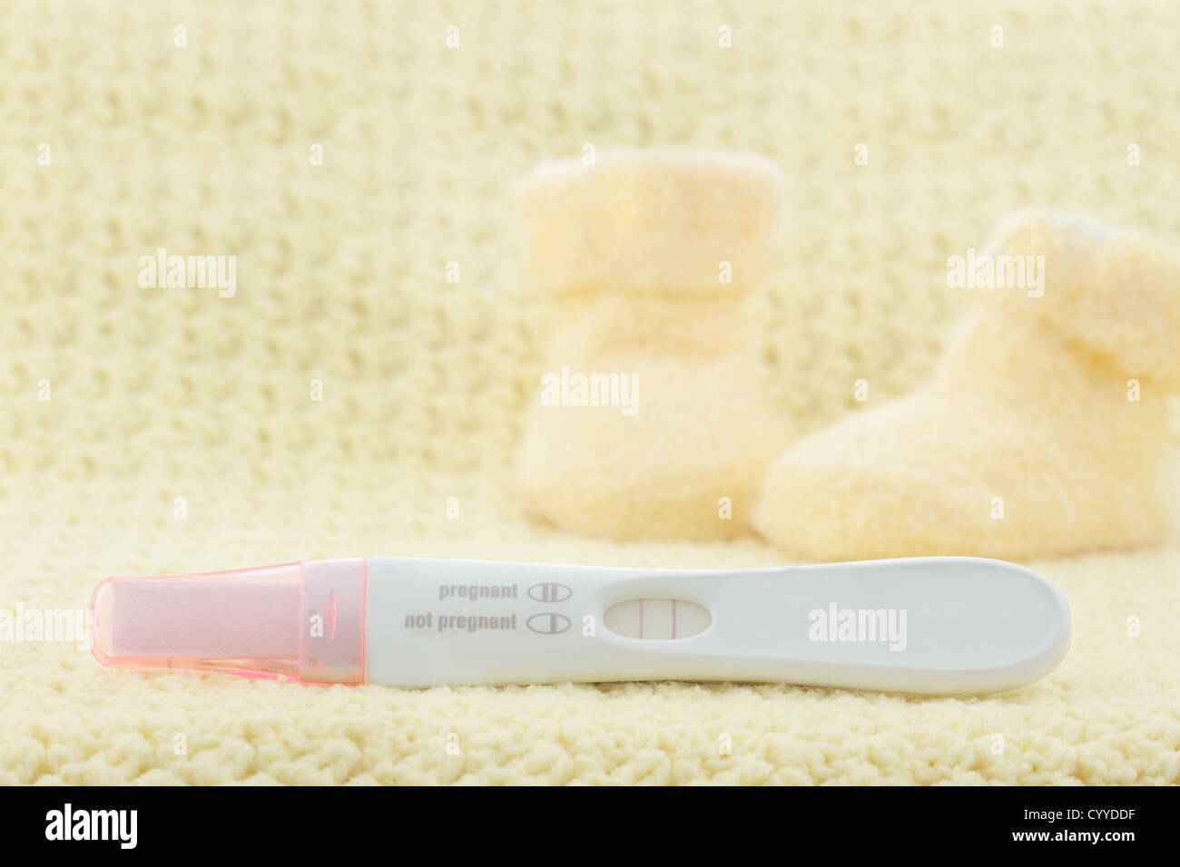 Positive pregnancy test with little cute baby booties in the background