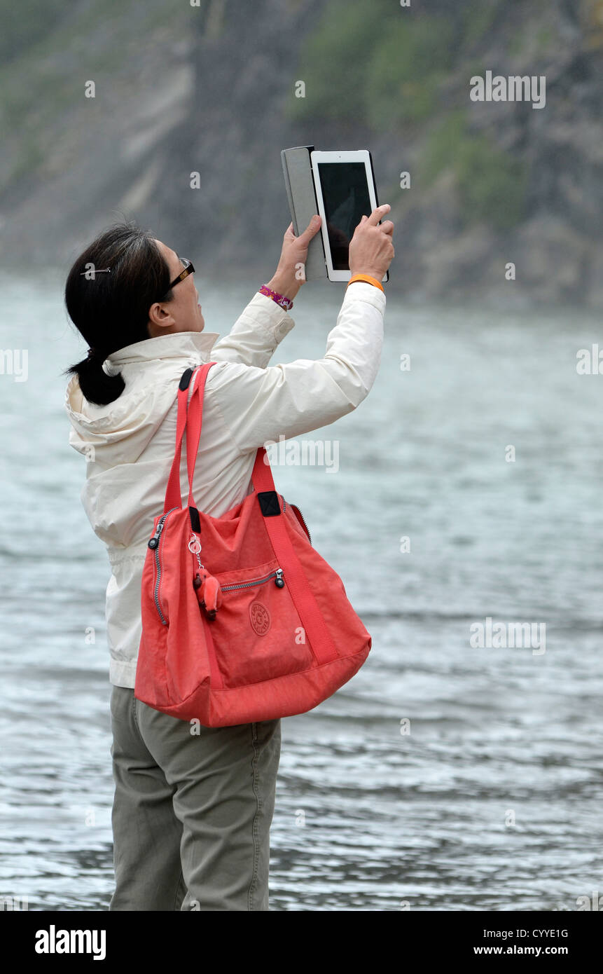 Woman taking picture with iPad, Mendenhall Glacier, Alaska. Stock Photo