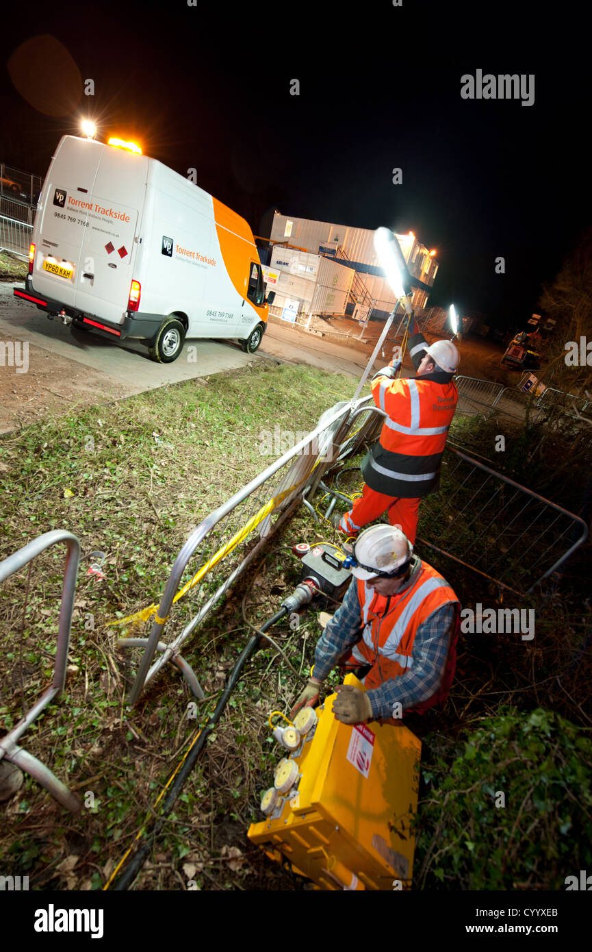 Workers erecting site lighting at night Stock Photo