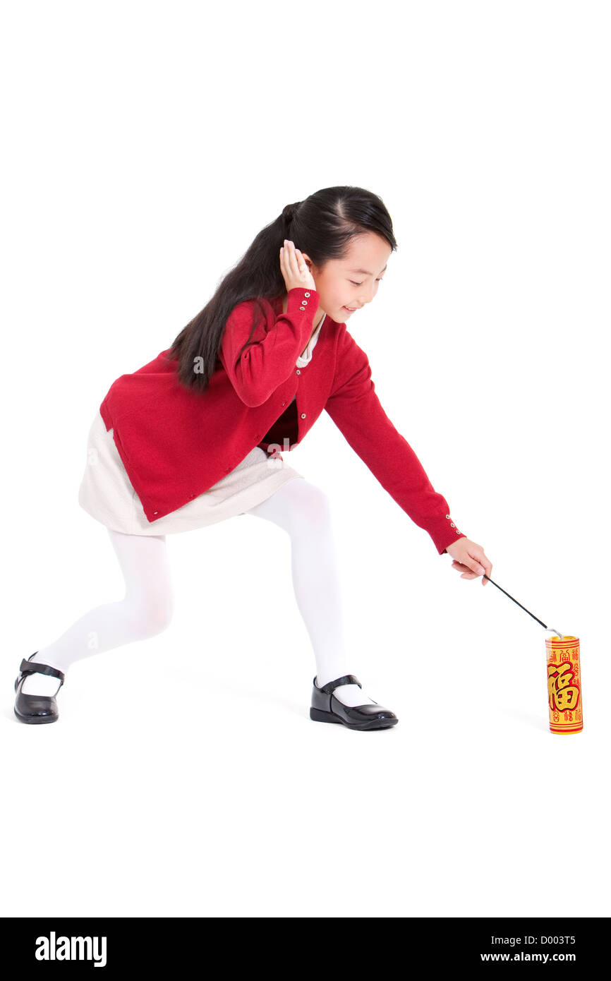 Little girl igniting firecracker with hands covering ears Stock Photo ...
