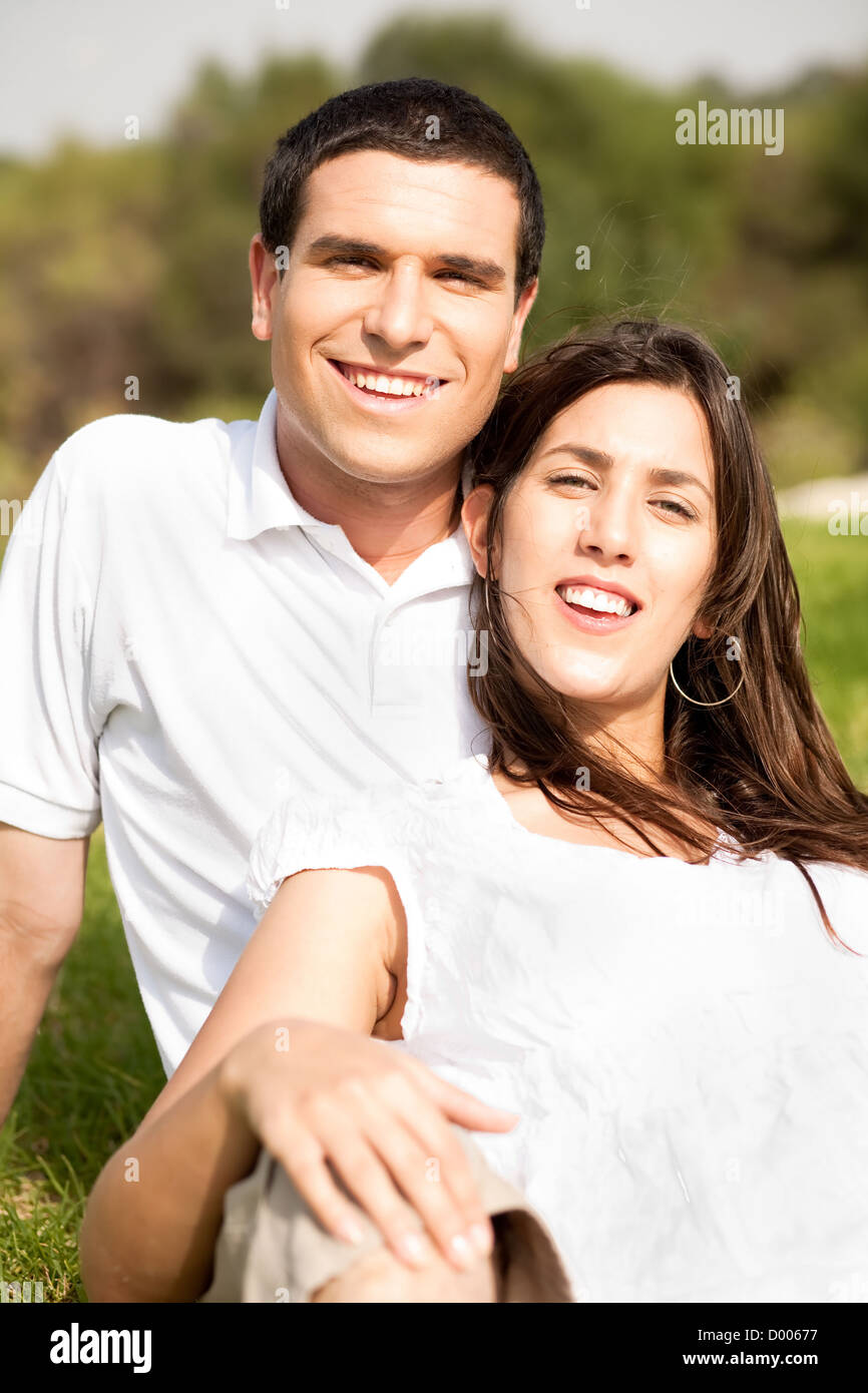 Portrait of Happy young couple sitting and smiling in the park Stock ...