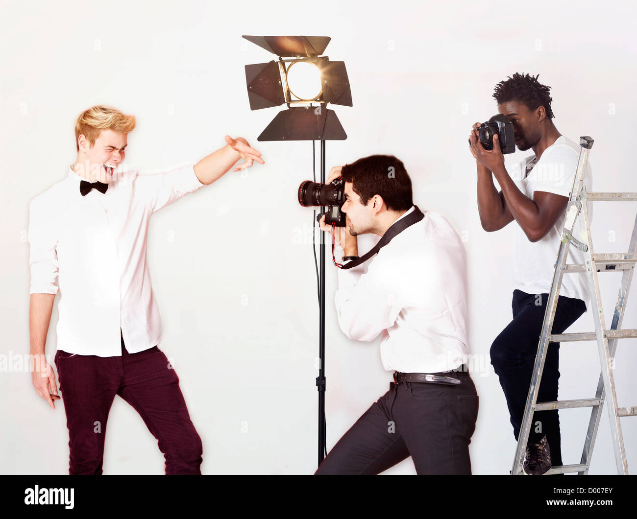 Paparazzi taking photographs of male actor over white background Stock Photo