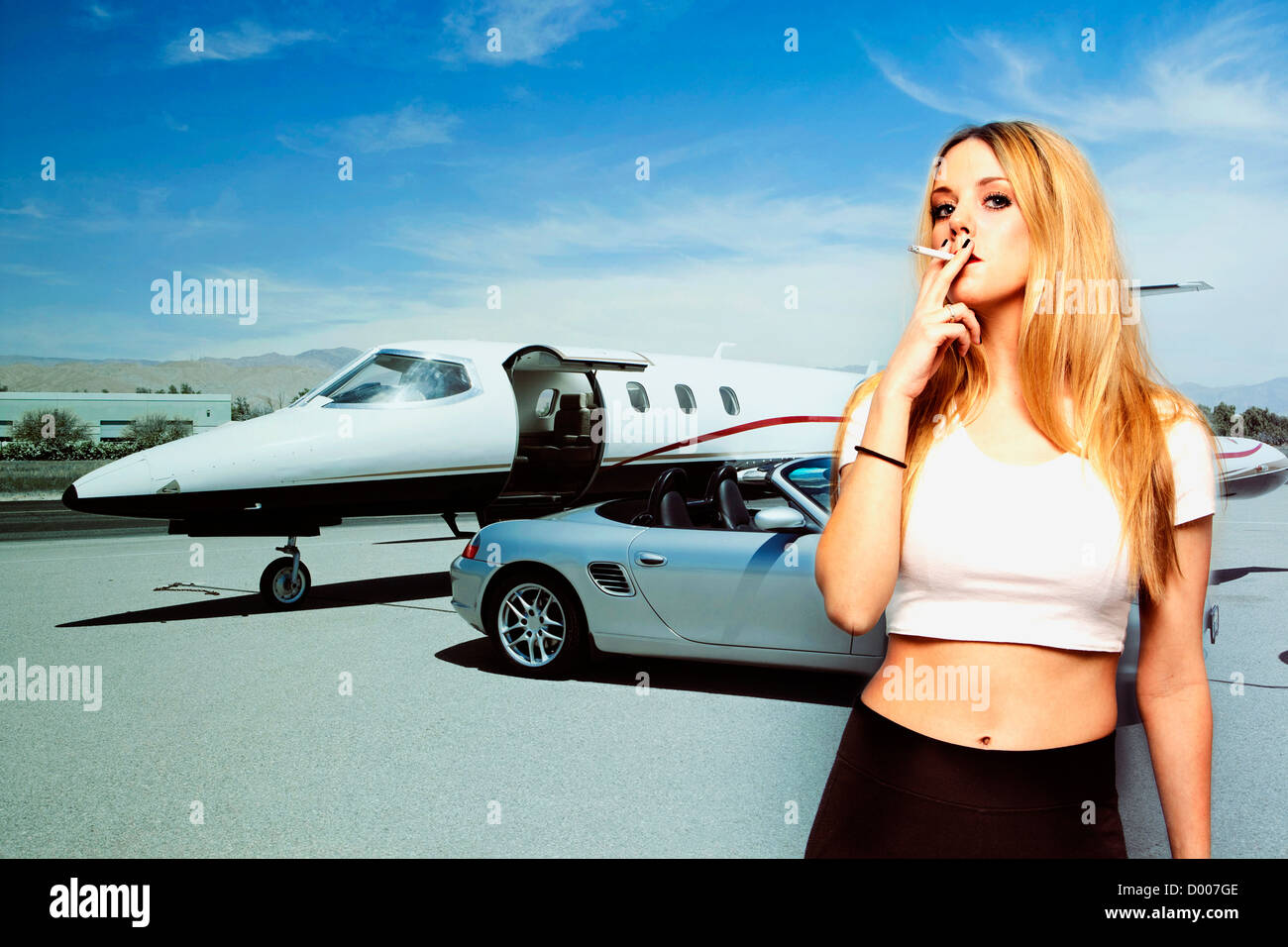 Portrait of young woman smoking cigarette with car and airplane in the background Stock Photo