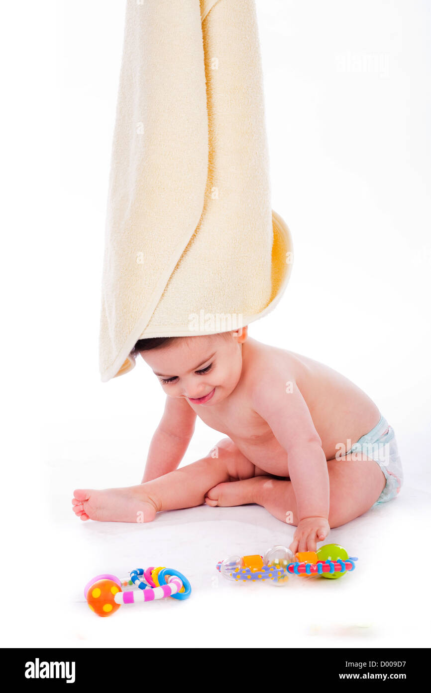 Baby with towel on its head while playing toys in a isolated background Stock Photo