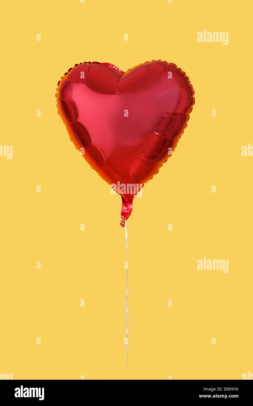 Red heart shaped balloon over yellow background Stock Photo - Alamy