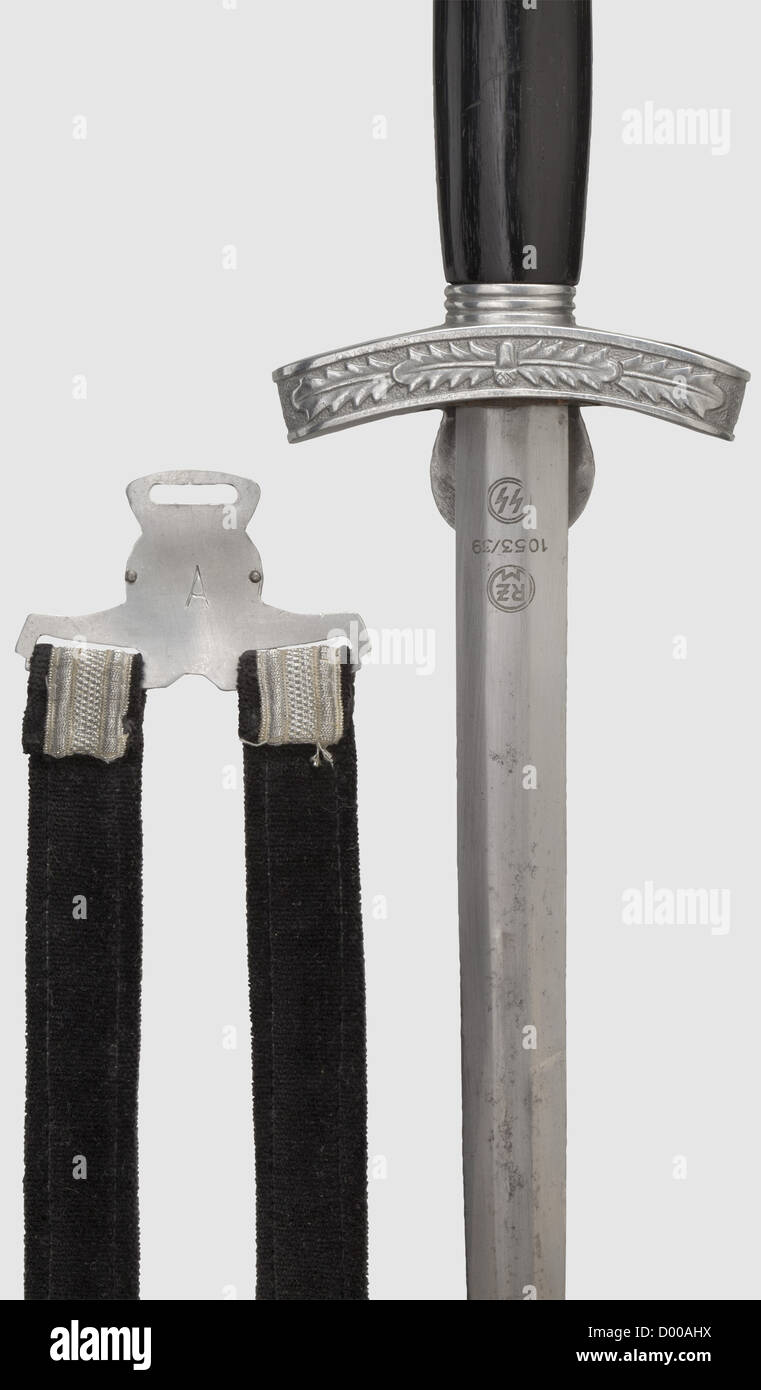 A replica dagger of the Germanic SS,Blade(stained,worn by cleaning)with etched motto 'Mijn Eer heet Trouw'(Meine Ehre heißt Treue = My Honour is Loyalty),maker 'RZM 1053/39 SS'. Aluminium crossguard and pommel,black wooden grip. Aluminium scabbard with nickel silver mouthpiece. Silver brocade suspension with black liner. Aluminium fittings,the separator fitted with a riveted emblem(Wolfsangel on a black-painted base). Length 40 cm. An excellent production from circa 1960,historic,historical,1930s,1930s,20th century,melee weapon,melee weapons,we,Additional-Rights-Clearences-Not Available Stock Photo