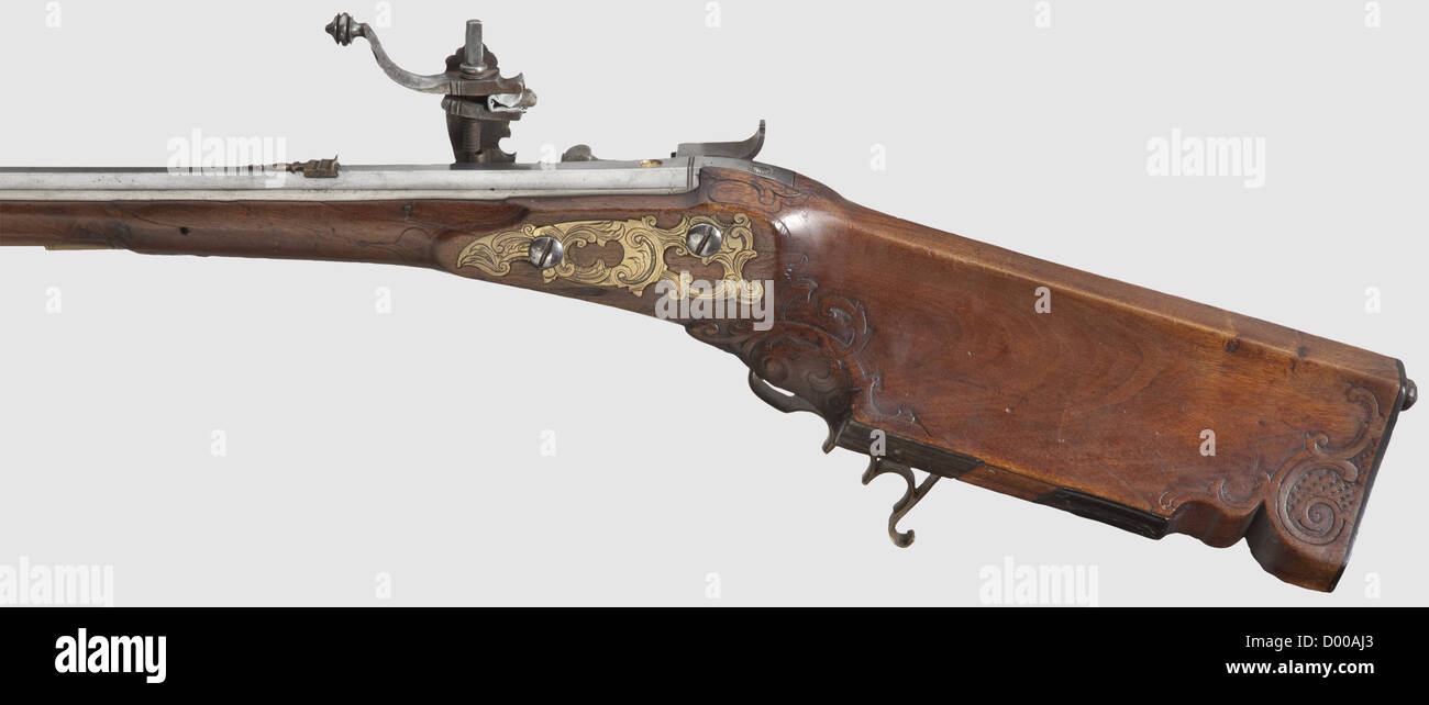A German wheellock rifle,Paul Lienhart,Munich,circa 1730.Slightly swamped,octagonal barrel with six-groove rifled bore in 12 mm calibre.Dovetailed brass front and rear sights.A brass filled master's mark,a lion above 'P.L.I.'(Stöckel No.688)on the chamber.The wheellock cut on the inside with floral designs.Hair set trigger.The lock plate finely engraved with riders and wild animals,and signed 'P.LIENHART IN MÜNCHEN' under the powder pan.Decoratively carved walnut full stock,the nosecap and the patchbox lid's ends of horn.Brass trigger guard an,Additional-Rights-Clearences-Not Available Stock Photo