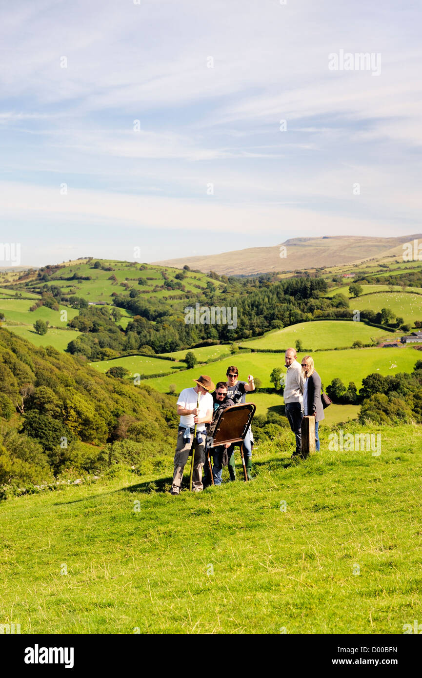 Walkers in Brecon Beacons National Park, Wales, UK. Reading information sign at Carreg Cennen castle. Black Mountain in distance Stock Photo