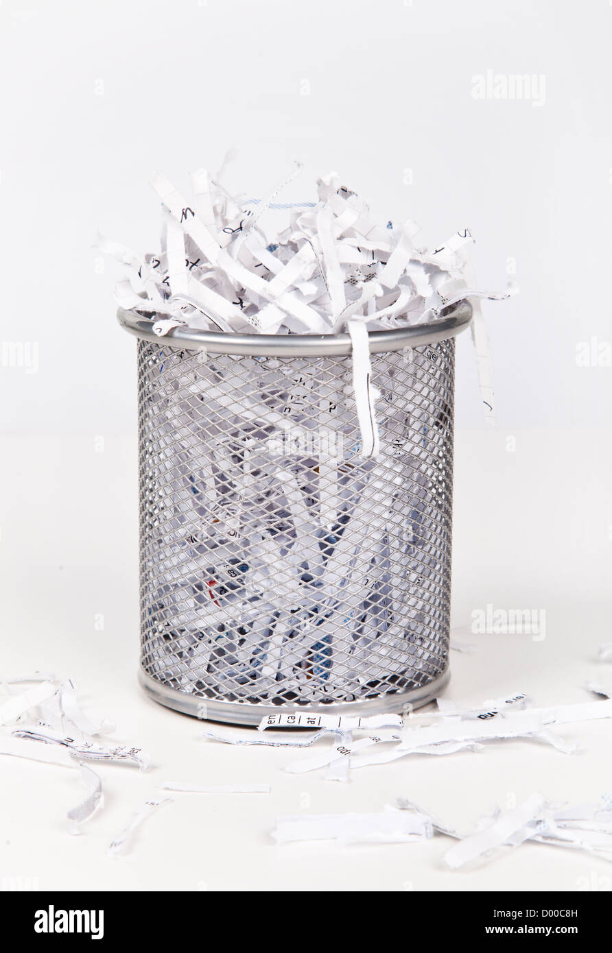 Wastepaper basket with papers lying around over white background Stock Photo