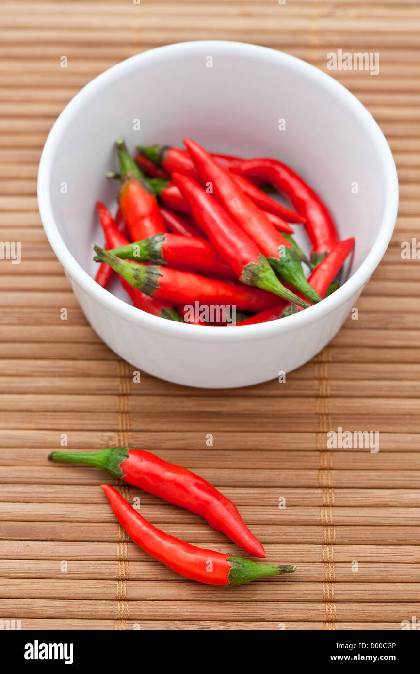 Hot chili peppers in a white bowl on a bamboo mat Stock Photo