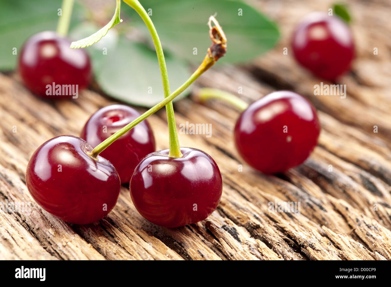 Cherries with leaves on a old wooden table. Stock Photo
