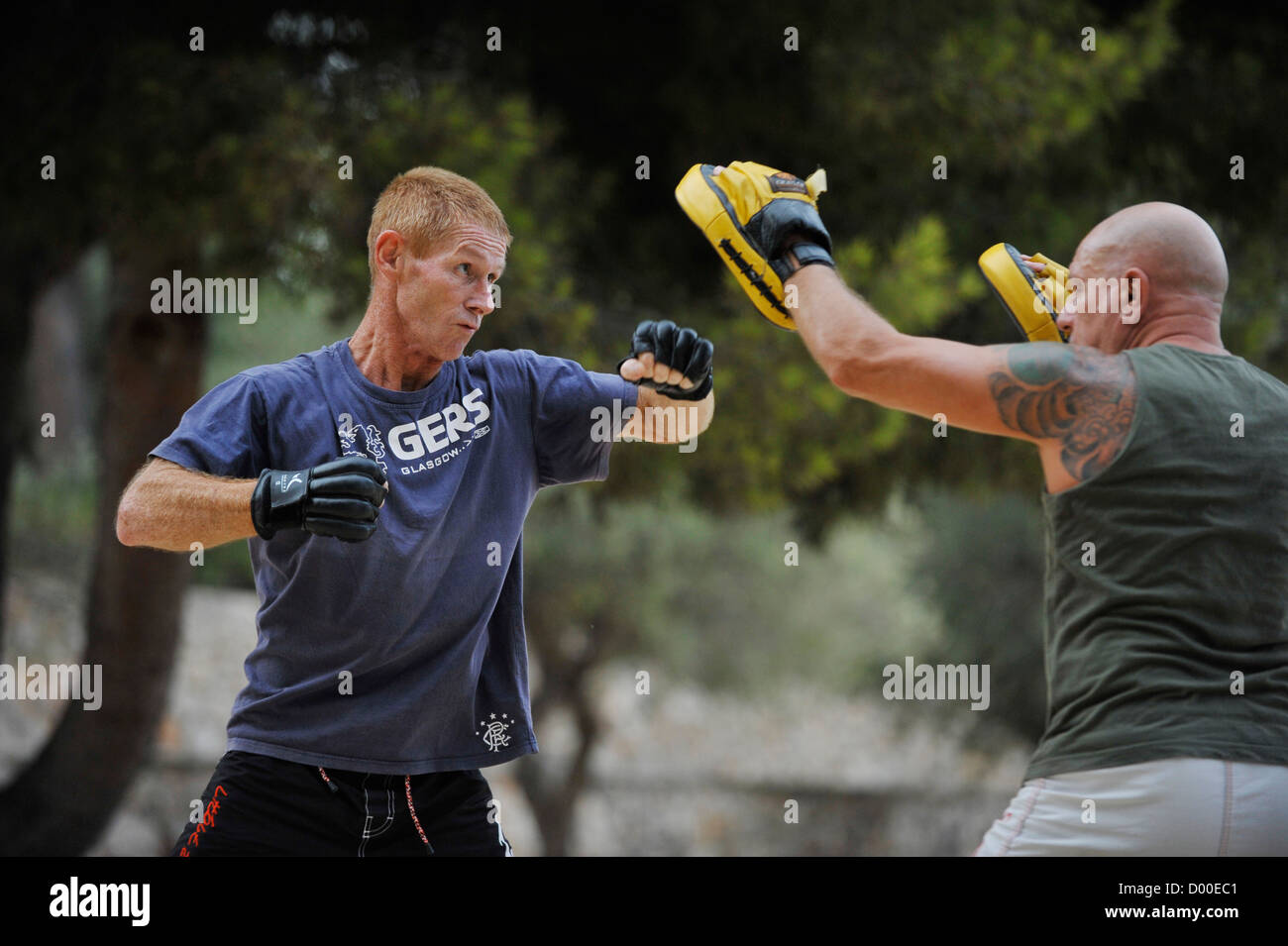 two men in their forties practice martial arts outdoors in a park Stock Photo