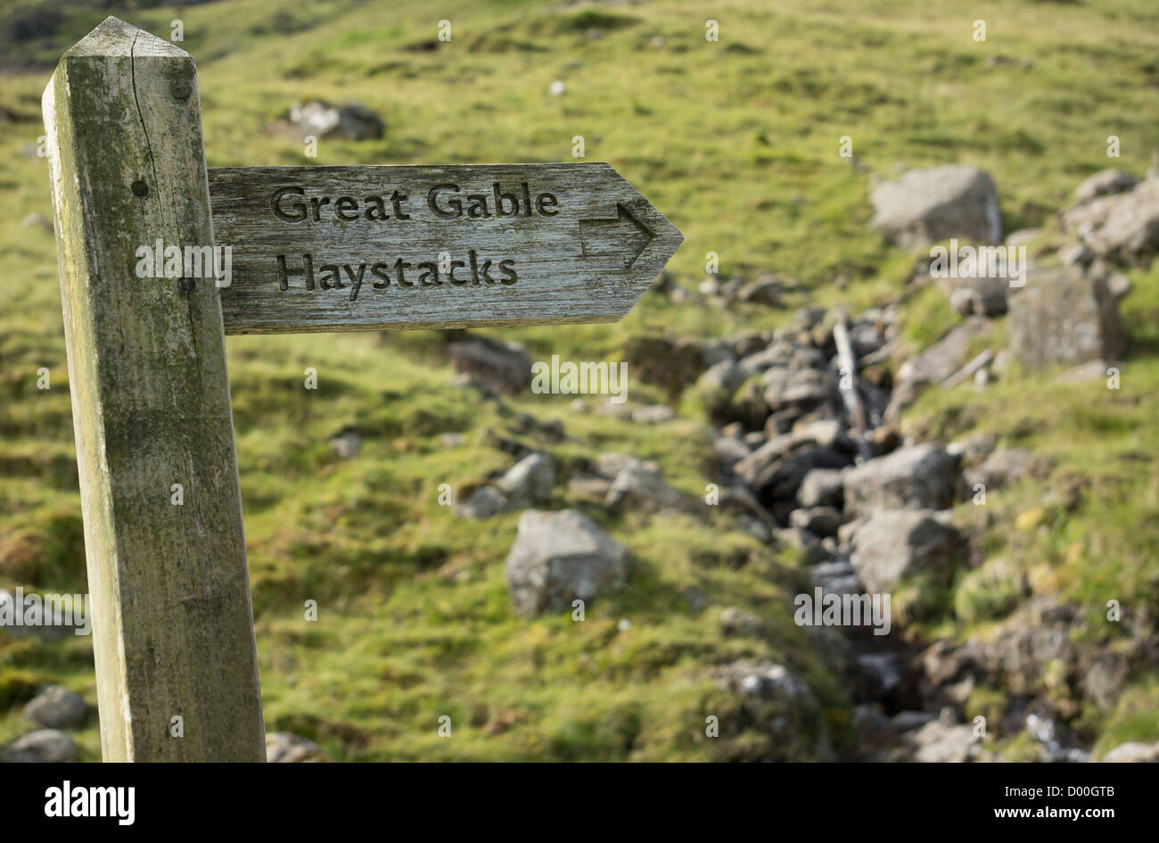 An old wooden signpost pointing the way towards Great Gable and Haystacks in the Lake District. Stock Photo