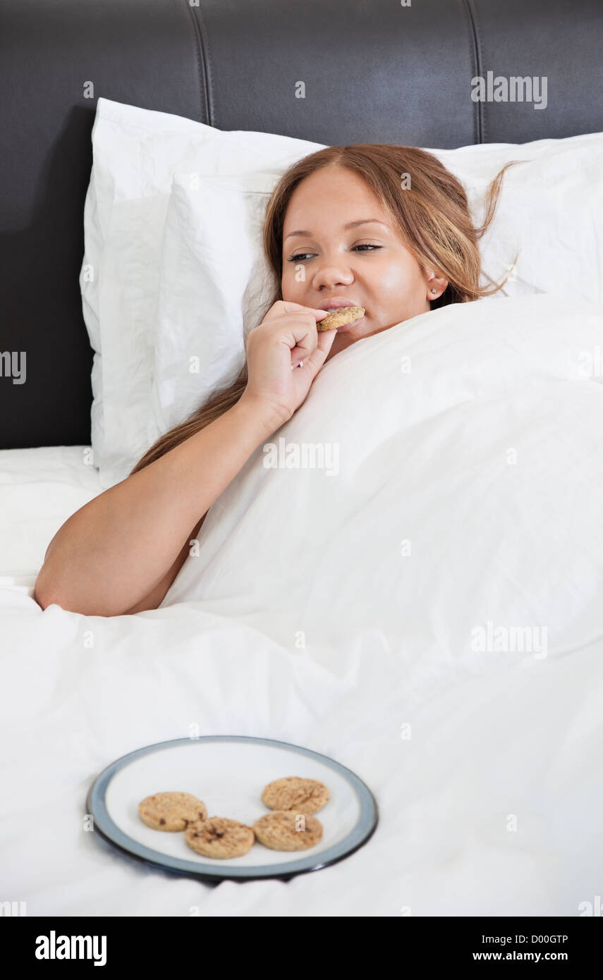 Young pregnant woman eating cookies in bed Stock Photo Alamy