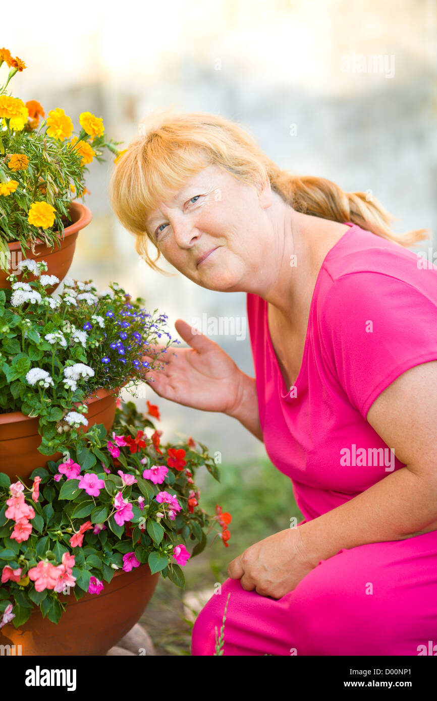 Senior woman enjoying own flowers in garden Stock Photo - Alamy
