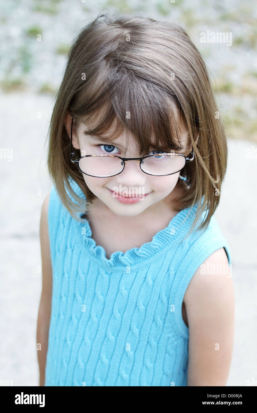Little girl outdoors wearing glasses and looking up into the camera. Stock Photo