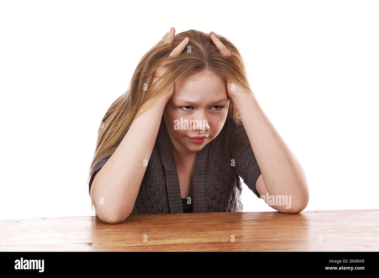 Sad and frustrated young girl sitting by table on white background Stock Photo