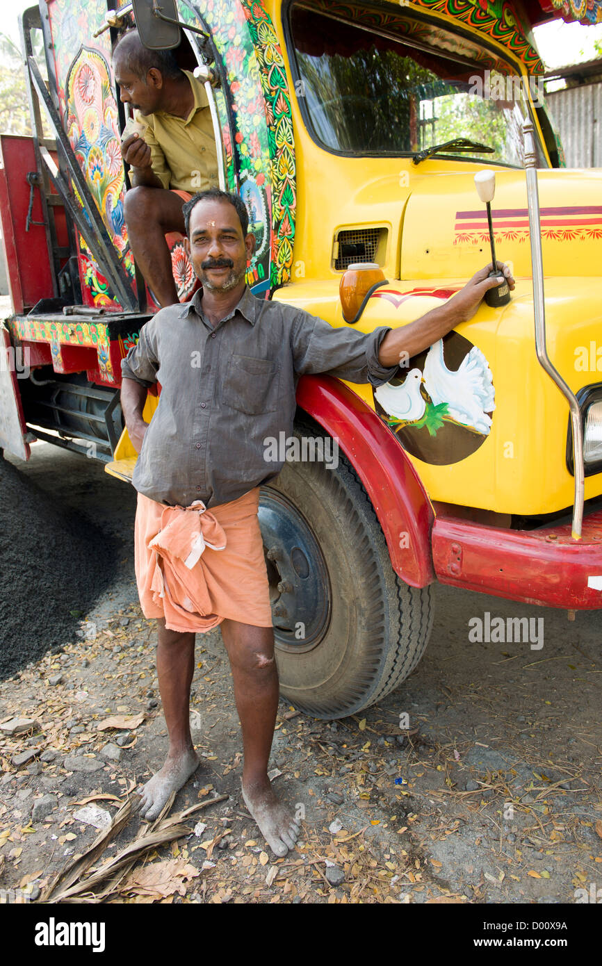 Man posing next to the brightly coloured cab of his lorry, Alappuzha (Alleppey), Kerala, India Stock Photo