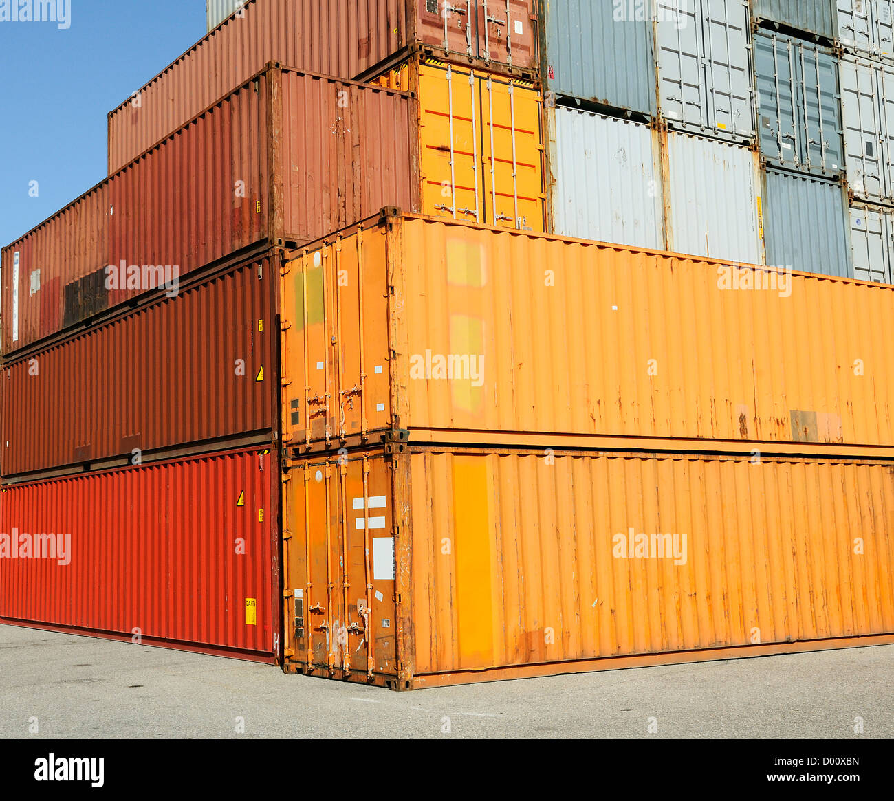Cargo shipping containers stacked at harbor freight terminal under clear blue sky Stock Photo
