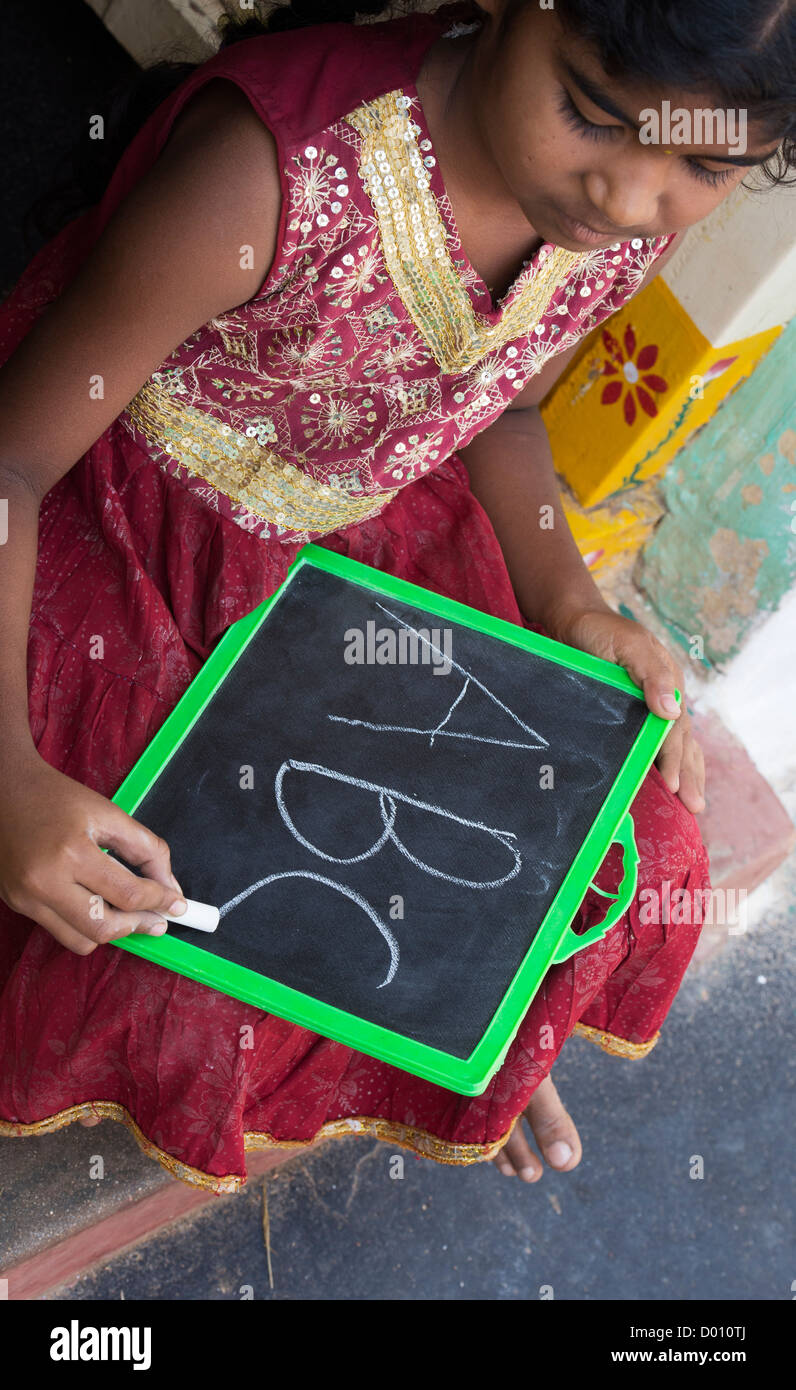 Indian village girl writing english alphabet on a chalkboard in a rural