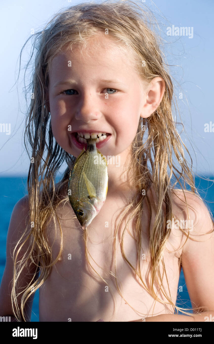 little girl with raw fish in the mouth Stock Photo - Alamy