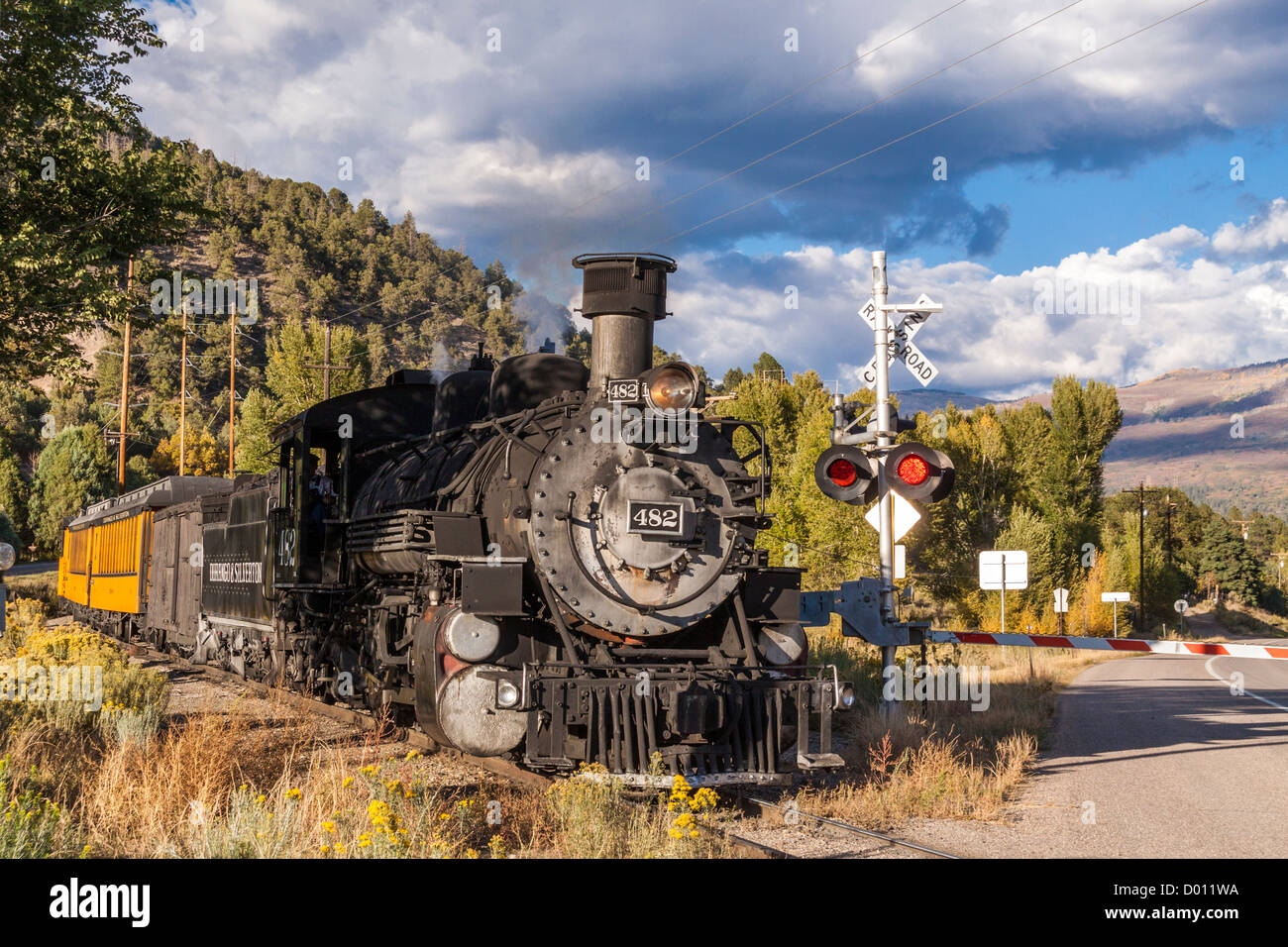 1925 Baldwin Steam Locomotive, 2-8-2 configuration, Mikado type, pulling historic classic railcars, crossing US 550 highway near Durango, Colorado. Stock Photo