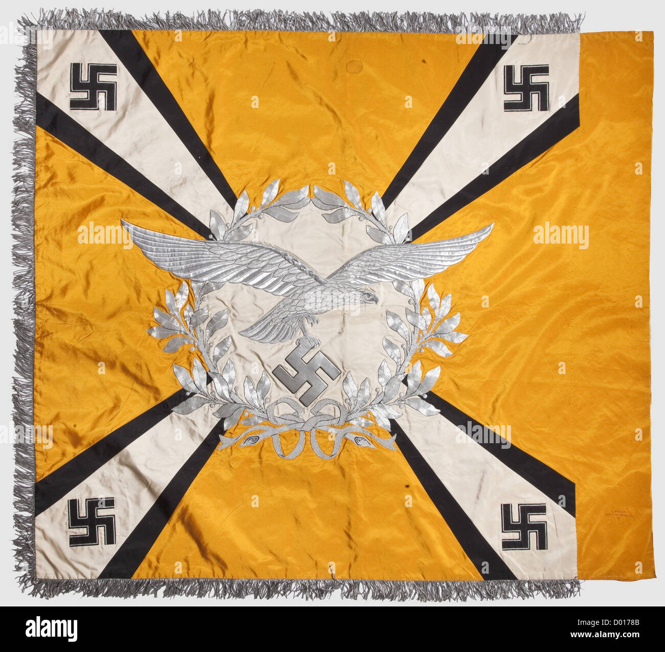A flag for flying or parachute troops,of yellow silk with lavish aluminium embroidery and silver fringe on three sides.Both sides with a white disc surrounded by an oak leaf wreath over four diagonal white beams,widening towards the corners and framed by black borders,each of silk.At the beam corners horizontal black silk swastikas with silver borders.At the centre of the disc on the right side,extending over the wreath,a Luftwaffe eagle embroidered in relief with different threads,on the left side is an Iron Cross.Embroidered maker's designation 'O.,Additional-Rights-Clearences-Not Available Stock Photo