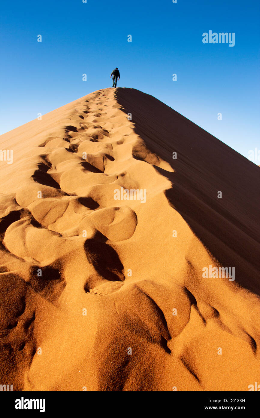 Man climbs up the dunes of Sossusvlei in Namibia Stock Photo