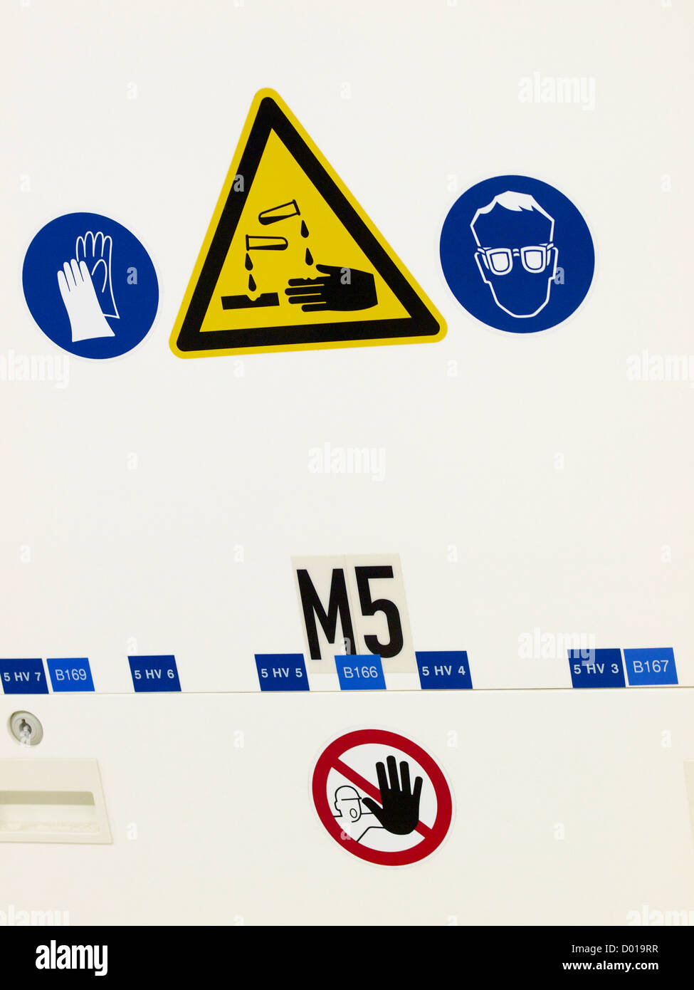 Various industrial warning stickers, gloves needed, danger corroding fluids, eye protection needed. Stock Photo