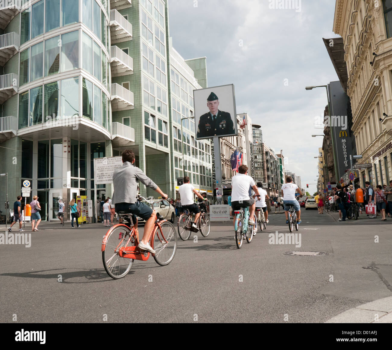 Cyclists ride past Checkpoint Charlie the former border crossing between east and west Berlin Germany Stock Photo