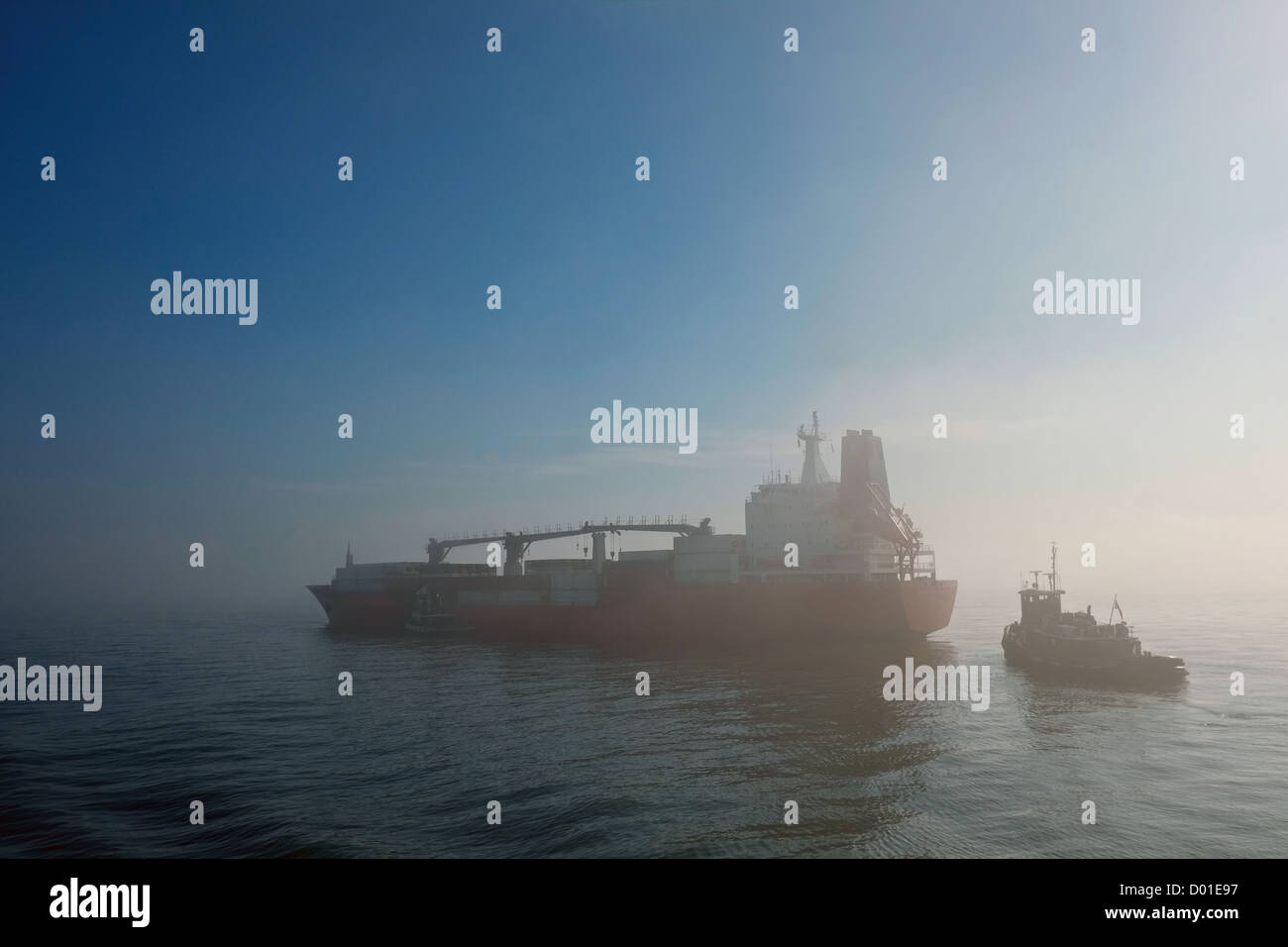Tugboat approaches container ship Albermarle Sound in fog in New York's Upper Bay. Stock Photo