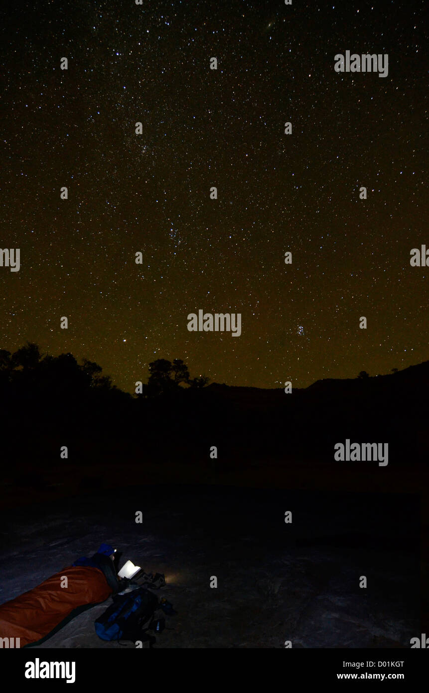 Backpacker reading a book while sleeping under the stars in the desert