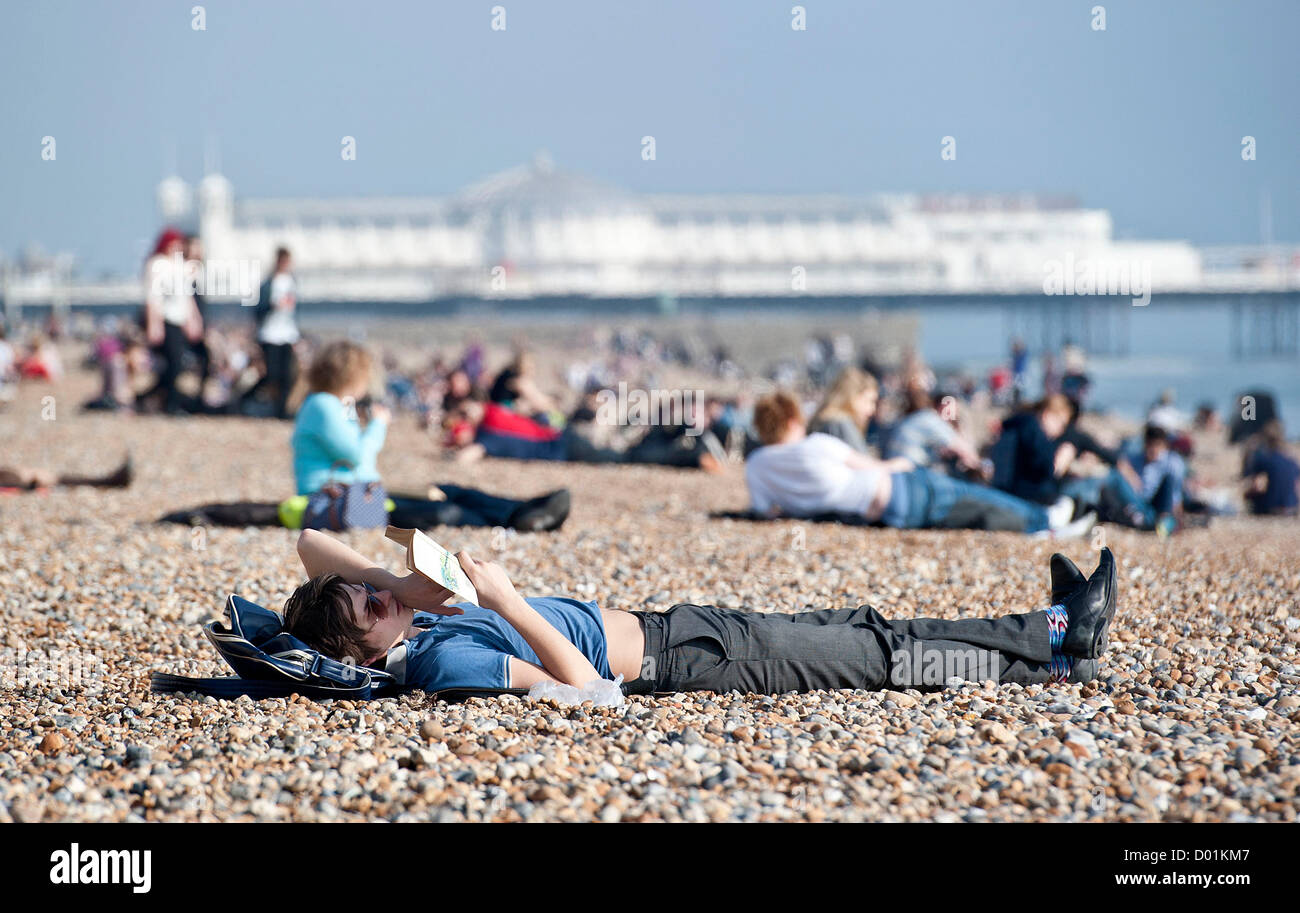 Hot weather hits the UK today with temperatures reaching unusually high for this time of year. Members of the public soak up the sun on Brighton beach, Sussex, UK Stock Photo