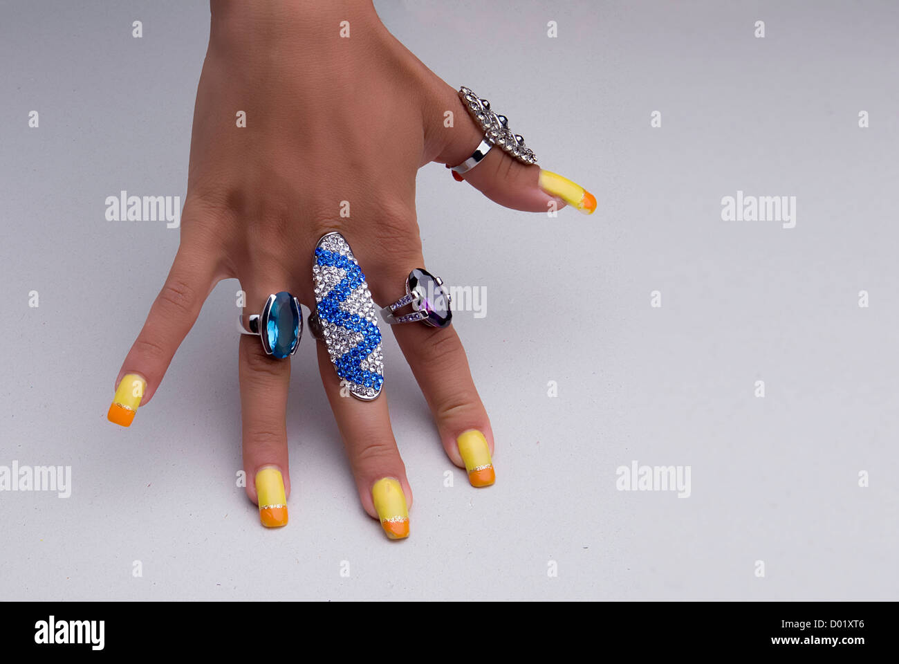 Hand showing big rings on fingers, colored nails Stock Photo - Alamy