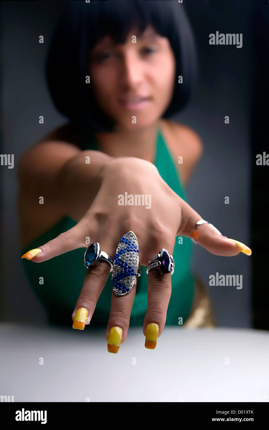 Hand showing big rings on fingers, colored nails Stock Photo - Alamy