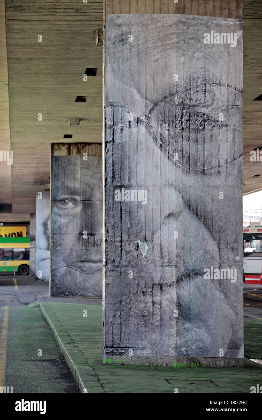 Large portrait photographs of old people on concrete road supports