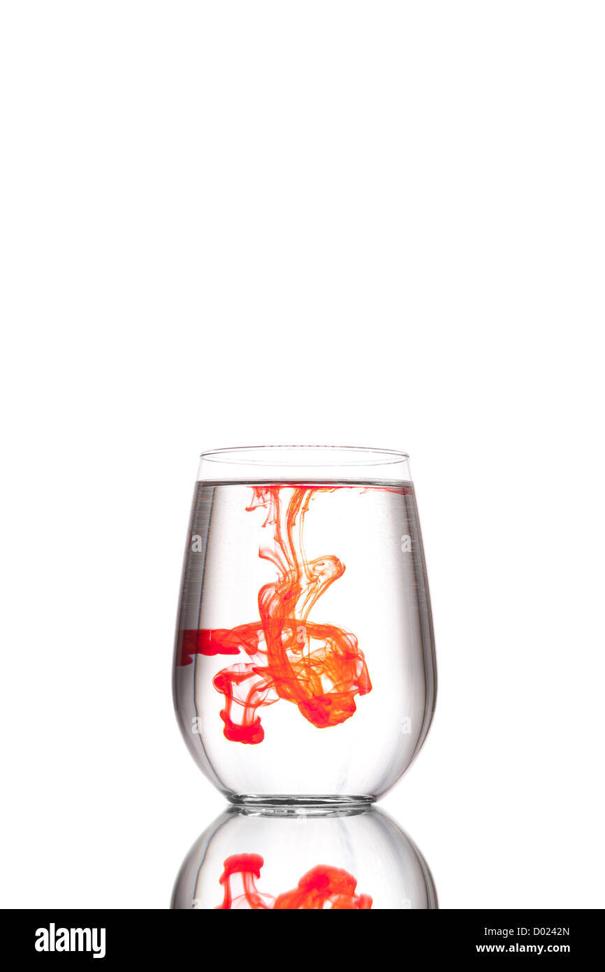 A clean, clear glass of water with a drop of red food coloring traveling through it, set against a white background. Stock Photo
