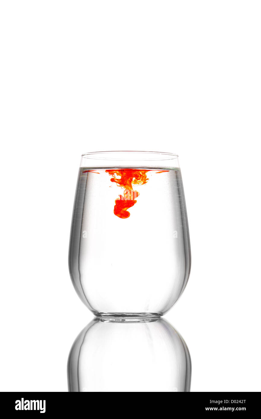 A clean, clear glass of water with a drop of red food coloring traveling through it, set against a white background. Stock Photo