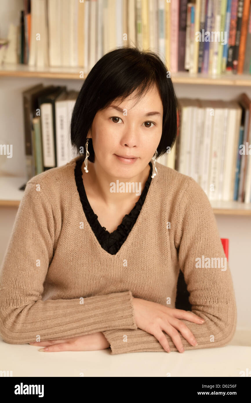 Business woman working at home sitting and looking at you, half length closeup portrait indoor. Stock Photo