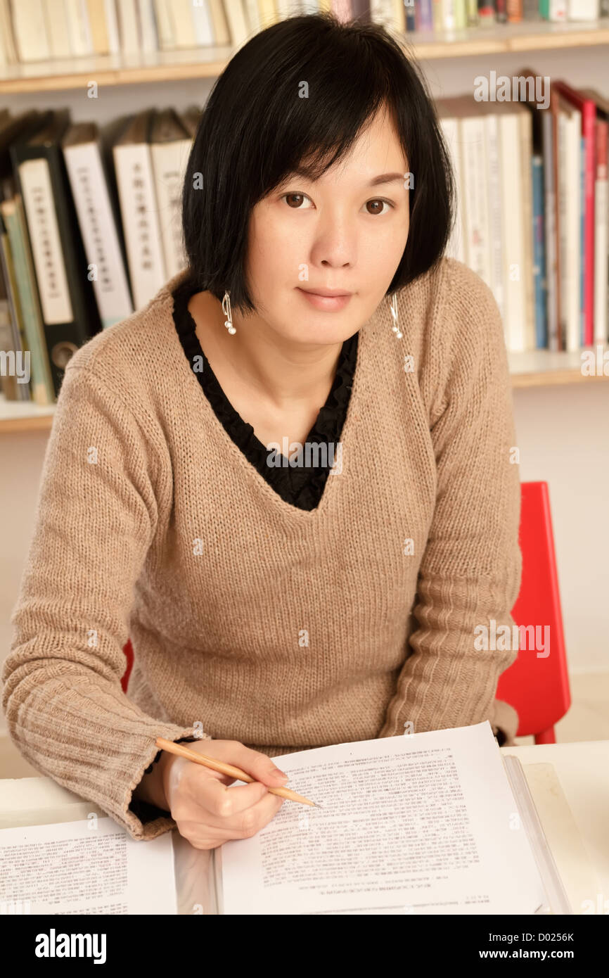 Business woman working at home sitting and looking at you, half length closeup portrait indoor. Stock Photo