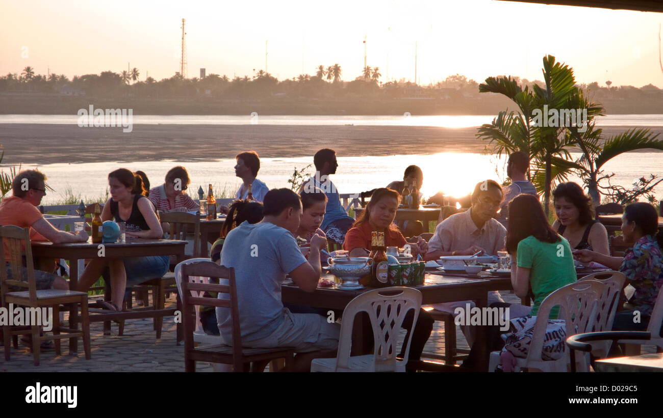 People enjoy drinks and food beside the Mekong River sunset Vientiane Laos PDR Stock Photo