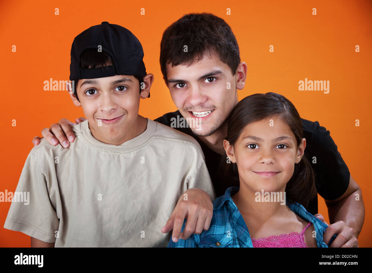 Smiling brothers and sister on an orange background Stock Photo