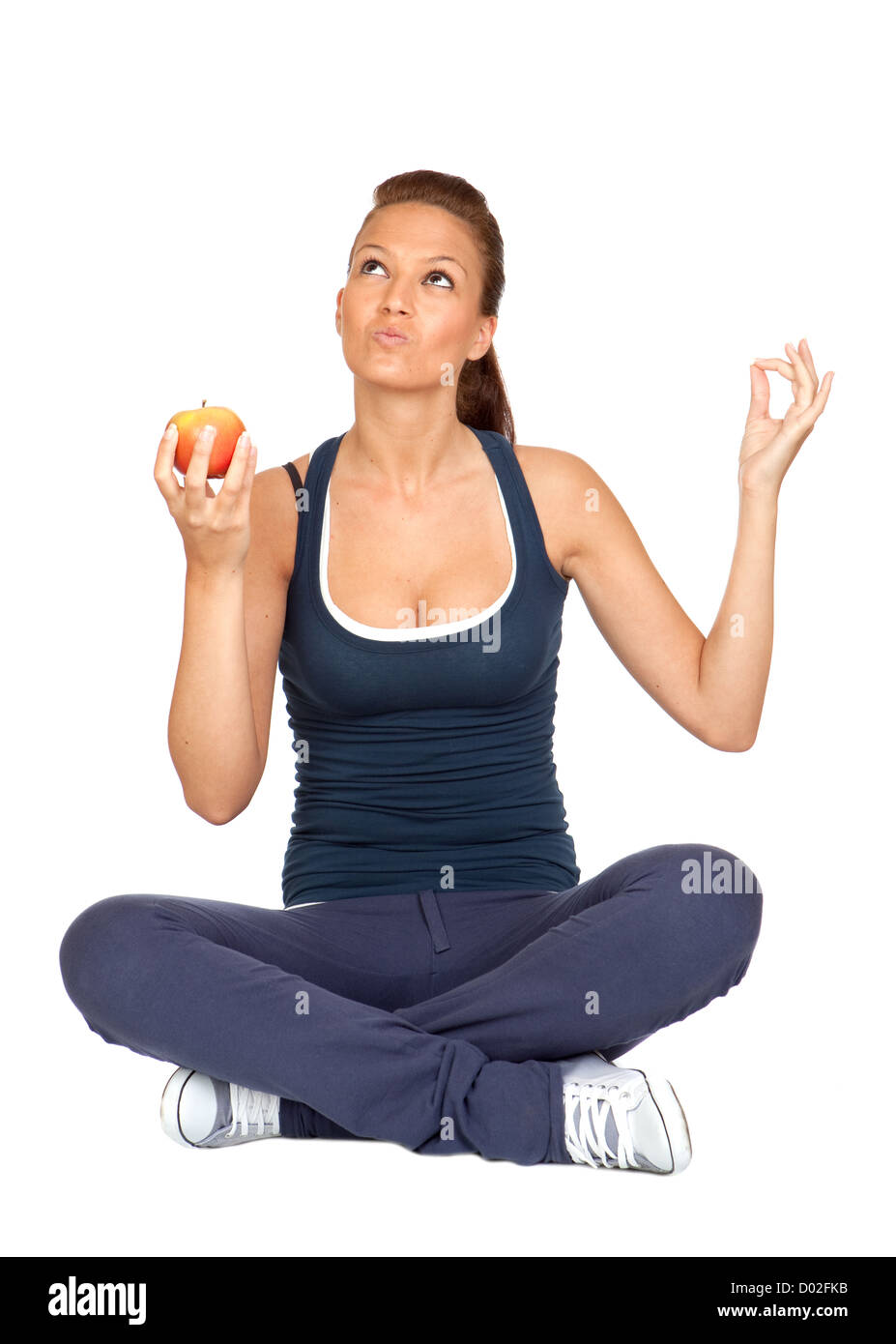 Gymnastics girl with an apple sitting with cross-legs on white background Stock Photo