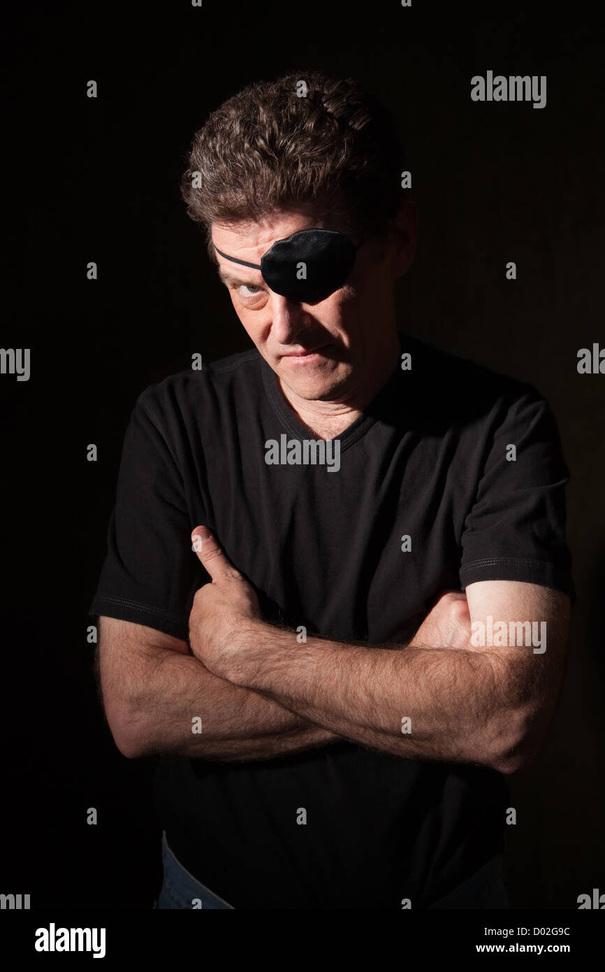 Young caucasian man on black background wearing an eyepatch Stock Photo