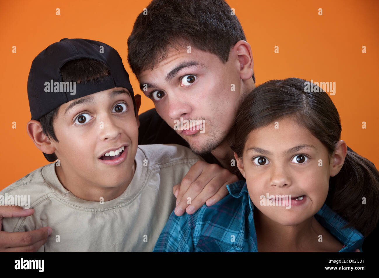 Elder brother with two younger siblings making faces Stock Photo